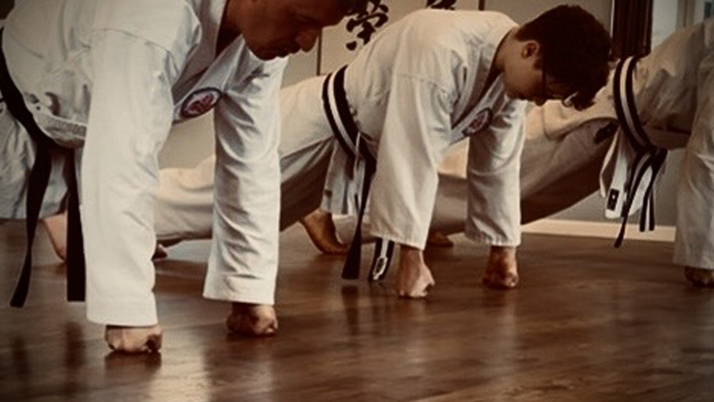Dan-Träger beim harten Qigong im Shirasagi Shima Dōjō, im Hintergrund das Waffengestell